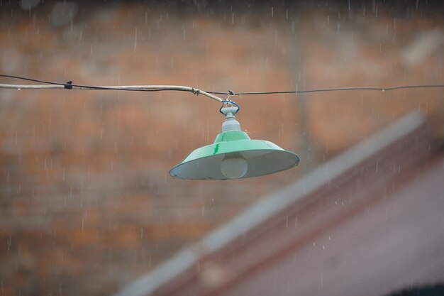 Una lampada appesa con una copertina verde durante una forte pioggia in un villaggio