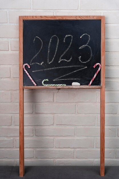 Una lavagna nera su cui è scritto in gesso l'anno 2023 Happy New Year