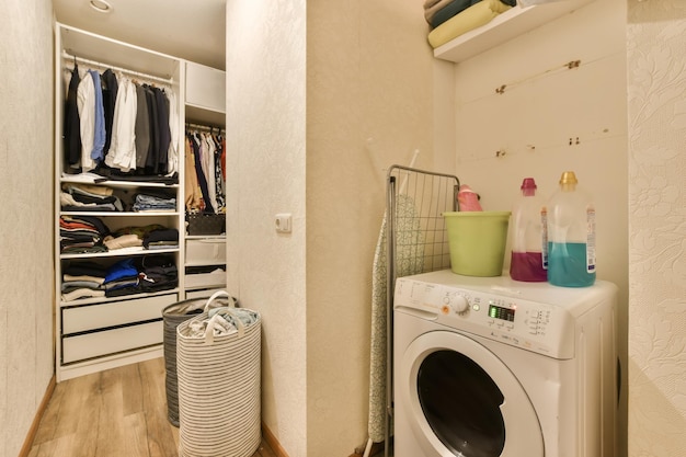 una lavanderia con un asciugatrice e vestiti appesi al muro accanto alla lavatrice