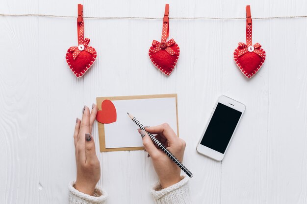 Una lettera d&#39;amore, cuori decorativi, regali e smartphone su un tavolo bianco per San Valentino