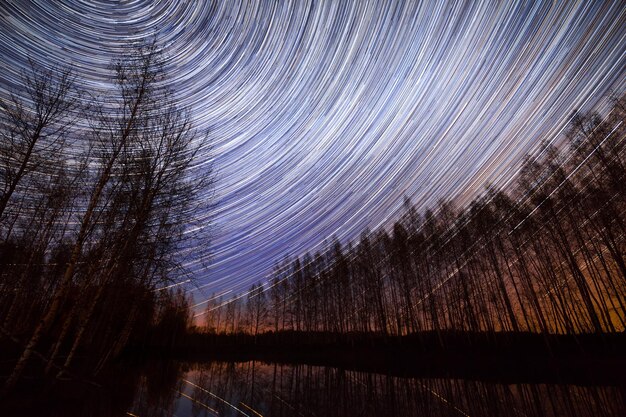 Una lunga esposizione del cielo sopra un lago con le tracce delle stelle