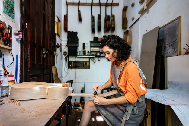 Una luthier che costruisce chitarre nel suo laboratorio di strumenti musicali