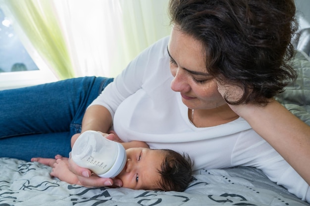 Una madre amorevole si prende cura del suo neonato La mamma nutre il suo neonato con un biberon