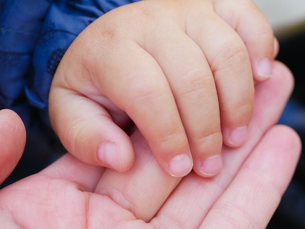 Una madre amorevole tiene la mano di un bambino. Mano di un neonato