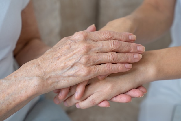 Una madre anziana calma sua figlia e la accarezza le tiene la mano in primo piano