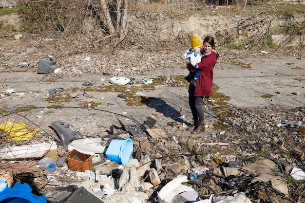 Una madre che guarda cose distrutte con un bambino in braccio