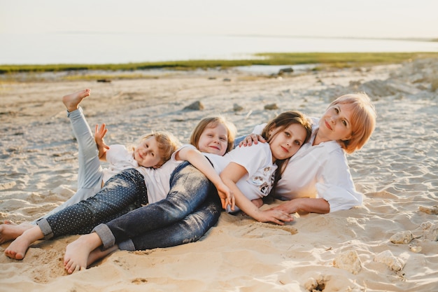 Una madre con le sue tre figlie giace sulla sabbia della spiaggia