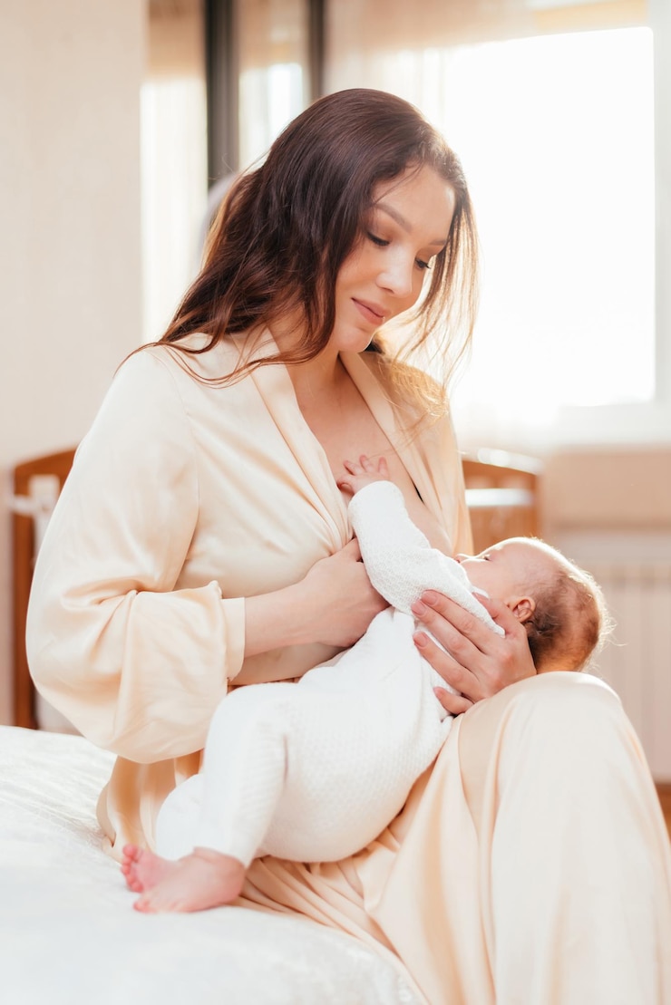 Una madre felice che allatta la sua bambina neonata nella sua camera da letto