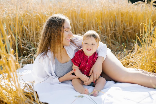 Una madre felice e il suo figlioletto sono sdraiati su una coperta a un picnic Passeggiata in famiglia nel campo