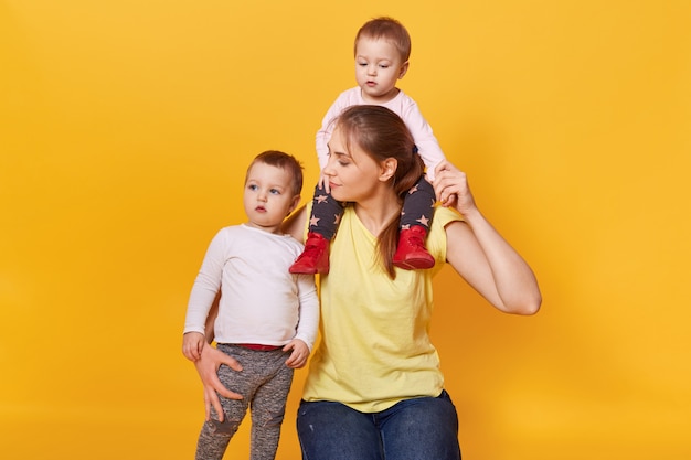 Una madre felice tiene stretto un bambino sul collo e un altro abbraccio stretto