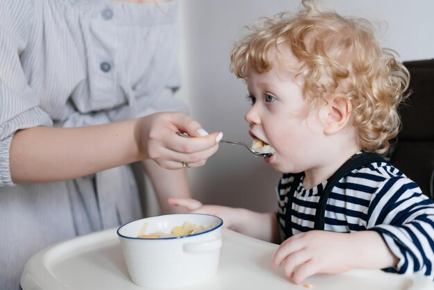 Una madre gentile e premurosa nutre il suo giovane figlio con un utile porridge una colazione di famiglia