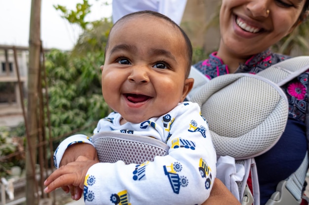 Una madre si diverte con il suo bambino carino in una borsa da trasporto portatile Esprimendo un caldo sentimento amorevole e premuroso Relazione familiare e concetto di cura del bambino