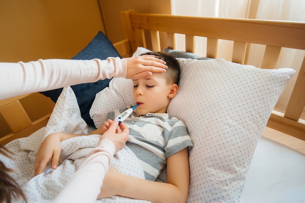 Una madre si prende cura di suo figlio che ha la febbre e la febbre. Malattia e assistenza sanitaria