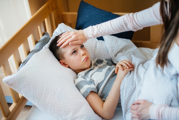 Una madre si prende cura di suo figlio che ha la febbre e la febbre. Malattia e assistenza sanitaria.