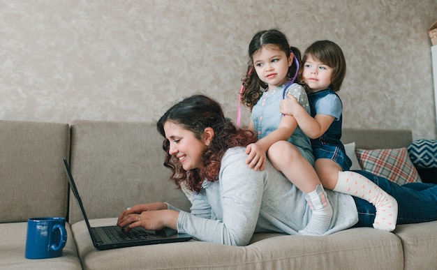 Una mamma felice cerca di lavorare e giocare con i suoi figli allo stesso tempo.