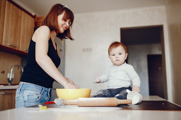 Una mamma giovane e bella sta preparando il cibo in cucina, insieme al suo piccolo figlio