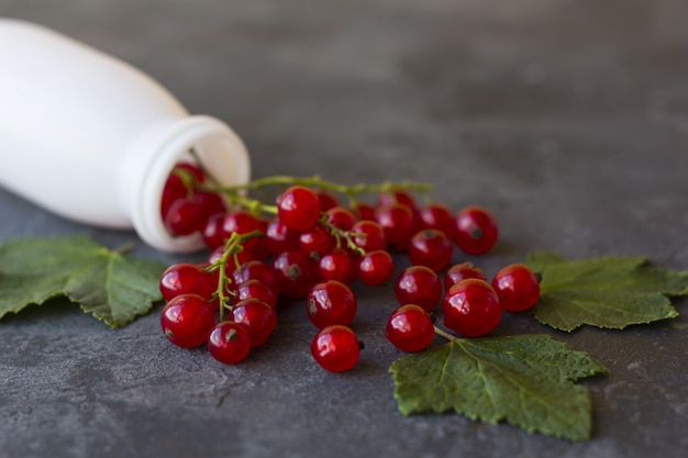 Una manciata di ribes rosso che cade da una bottiglia