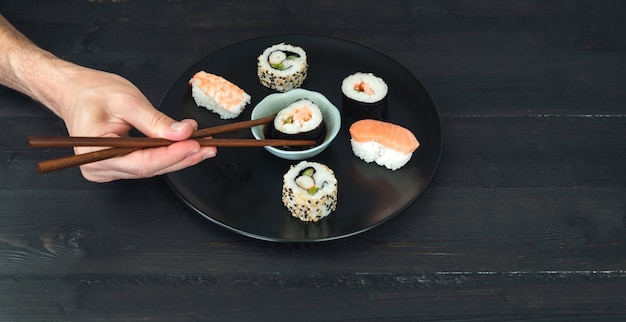 Una mano che immerge un rotolo di sushi nella salsa