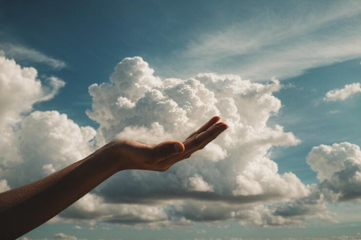 Una mano che si alza verso il cielo e stringe tra le sue mani un ammasso di soffici nuvole bianche