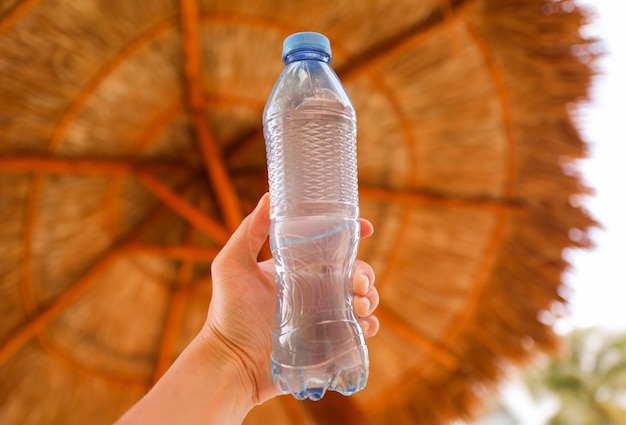 Una mano che tiene una bottiglia d'acqua con su scritto "acqua".