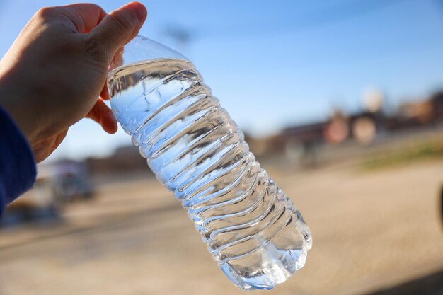 Una mano che tiene una bottiglia d'acqua con su scritto "acqua".