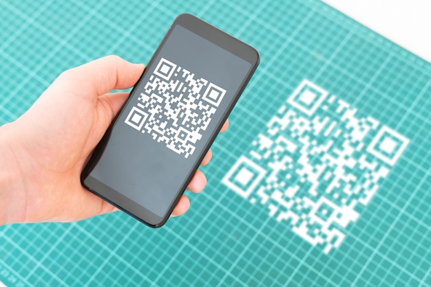 Una mano che tiene uno smartphone e scansiona il codice qr per effettuare un pagamento