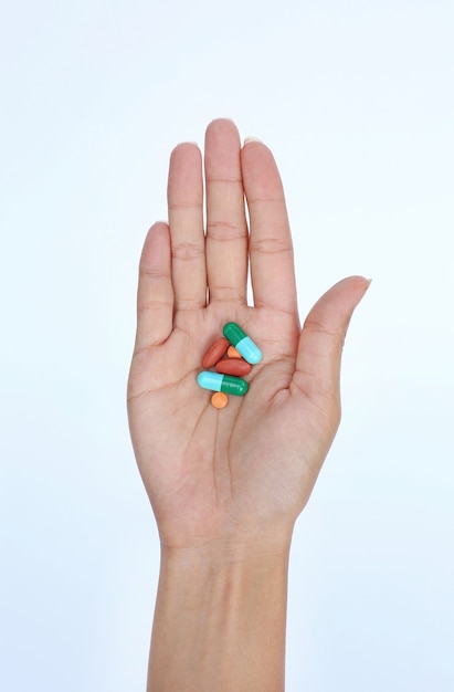 Una mano di una donna con alcune pillole su sfondo bianco