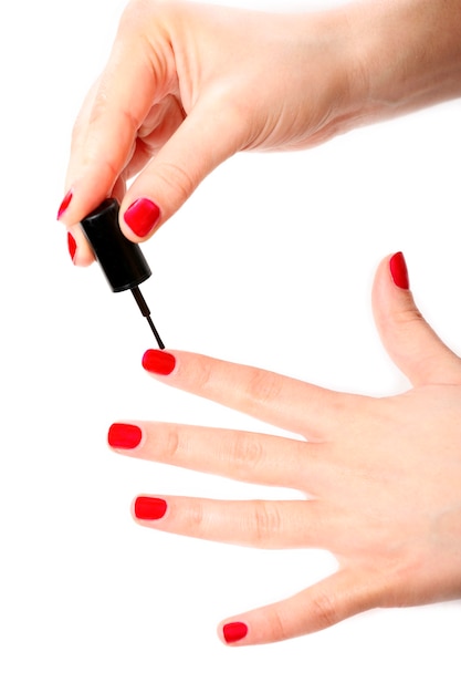 una mano femminile che si dipinge le unghie di rosso su sfondo bianco