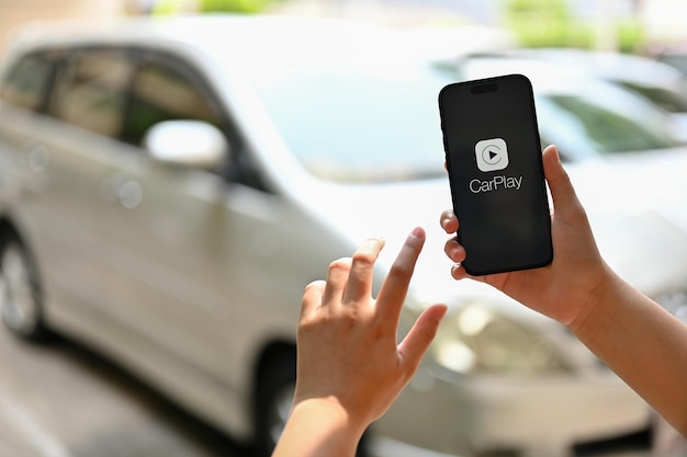 Una mano femminile che tiene un iPhone con il logo CarPlay sullo schermo