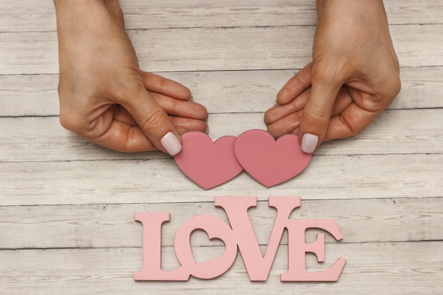 Una mano femminile tiene un cuore di legno, il concetto di amore