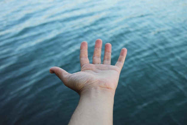 Una mano si allunga verso l'acqua per mostrare che l'acqua è blu.