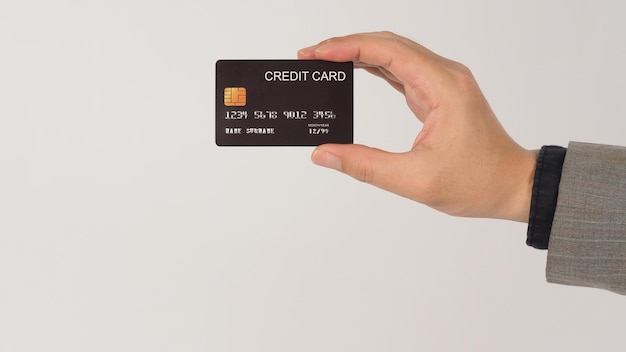 Una mano tiene le carte di credito nere e indossa un abito su sfondo bianco.