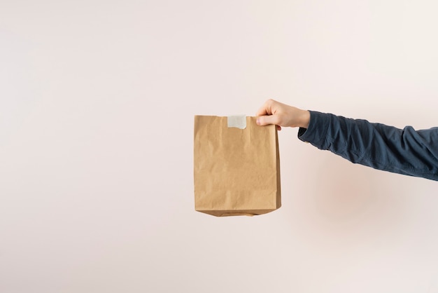 Una mano tiene un pacco di carta con cibo consegnato a casa