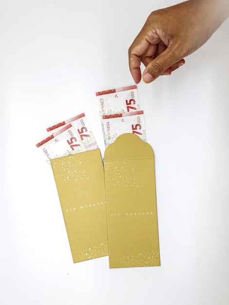 Una mano tiene una banconota da 5 euro in una busta dorata con sopra il numero 5.