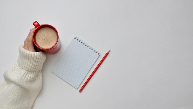 Una mano, un blocco, una tazza di caffè su una sedia. Fare un piano per il nuovo anno