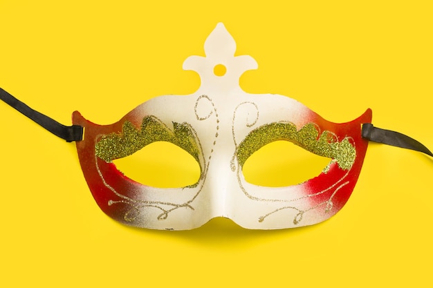 Una maschera di carnevale rossa e bianca su sfondo giallo con spazio di copia