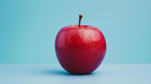 Una mela rossa vivace e croccante su uno sfondo blu La mela è perfettamente rotonda e senza macchie con una pelle liscia e lucida