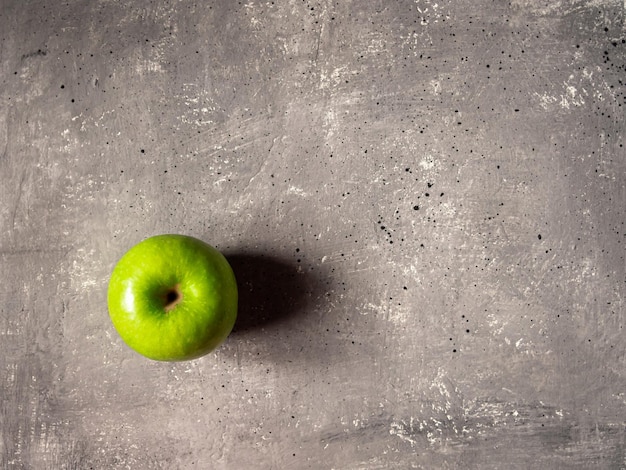 Una mela verde su sfondo grigio cemento