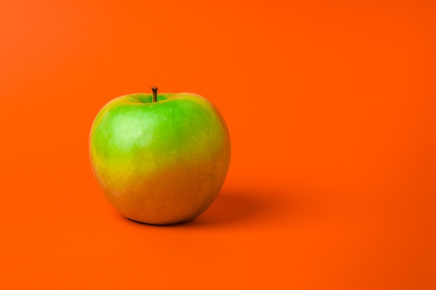 Una mela verde su uno sfondo arancione. Minimalismo e copia spazio