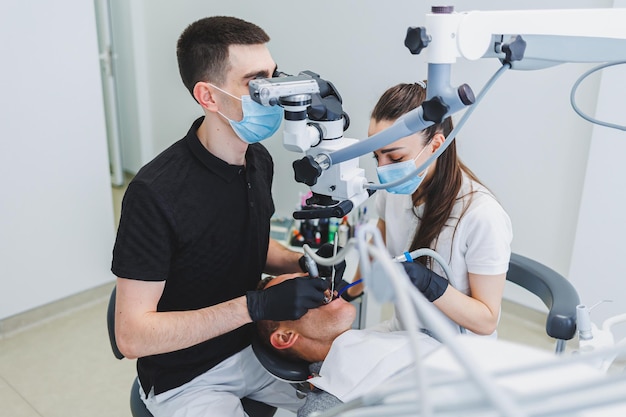Una moderna clinica odontoiatrica con un microscopio per il trattamento dei pazienti Un dentista utilizza un microscopio per esaminare i denti di un paziente Clinica odontoiatrica di attrezzature mediche