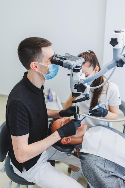 Una moderna clinica odontoiatrica con un microscopio per il trattamento dei pazienti Un dentista utilizza un microscopio per esaminare i denti di un paziente Clinica odontoiatrica di attrezzature mediche