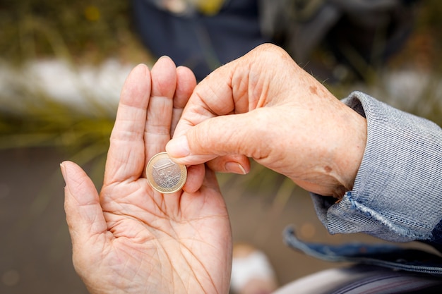 Una moneta da un euro nelle mani di una signora anziana