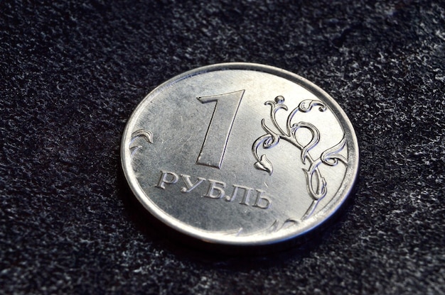 Una moneta da un rublo russo giace su uno sfondo di metallo scuro. Traduzione in primo piano del testo sulla moneta quot1 rublequot