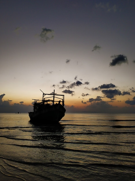 Una nave abbandonata in acque poco profonde vicino alla spiaggia al tramonto.