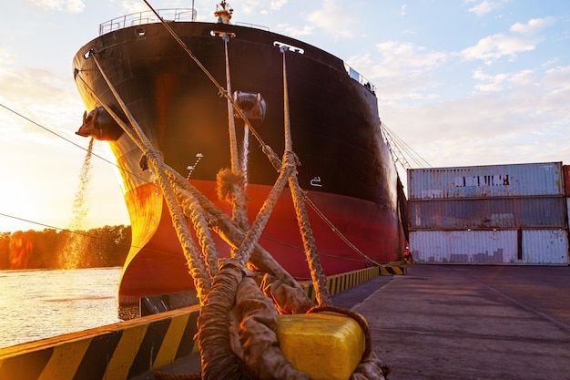 Una nave da carico ormeggiata alla bitta di ormeggio del porto con funi