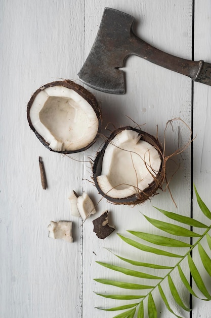 Una noce di cocco viene tagliata a metà su un tavolo di legno chiaro Vista dall'alto