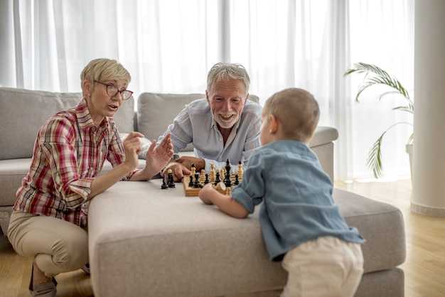 Una nonna e un nonno che giocano a scacchi con il nipote