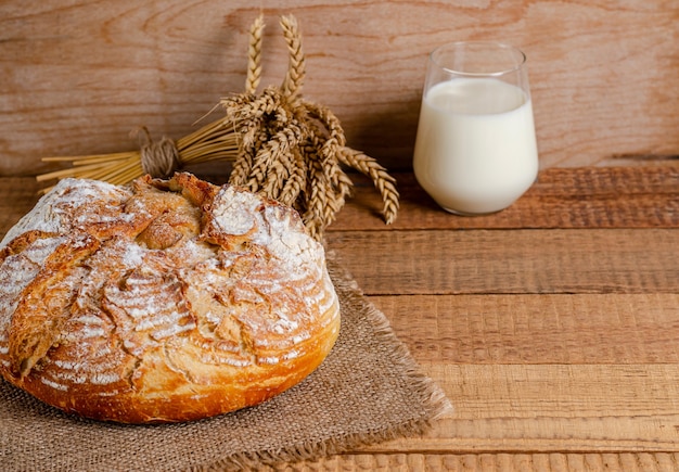 Una pagnotta di farina di frumento, un bicchiere di latte su assi di legno