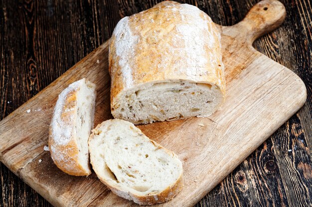 Una pagnotta di pane di grano fresco sul tavolo durante la cottura, pane fresco morbido con semi di zucca e semi di lino