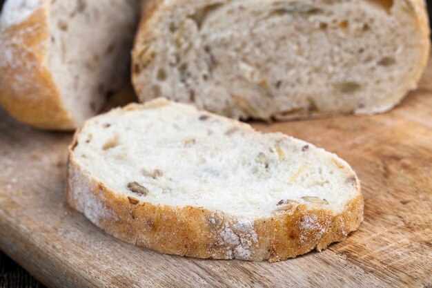 Una pagnotta di pane di grano fresco sul tavolo durante la cottura, pane fresco morbido con semi di zucca e semi di lino